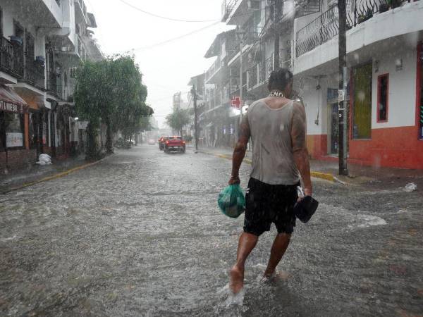 Un hombre camina por una calle inundada por lluvias provocadas por Simón este martes, mientras la tormenta tropical Trudy se formaba en el Pacífico mexicano a partir de la depresión tropical Veintiuno-E, en Puerto Vallarta (México).