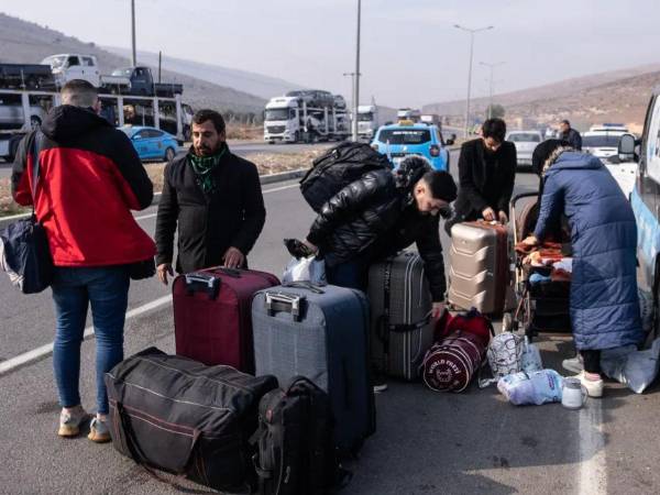 Sirios con sus pertenencias esperan para cruzar a Siria desde Turquía.
