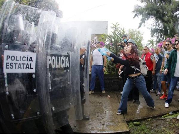 Personas se enfrentan con integrantes de la policía antimotines este domingo en Guadalajara.