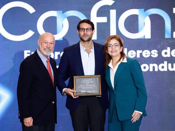 Rodrigo Canahuati y Ruth Marie Canahuati reciben en nombre de Jorge Canahuati Larach, presidente de Grupo Opsa, el reconocimiento de manos de Italo Pizzolante.