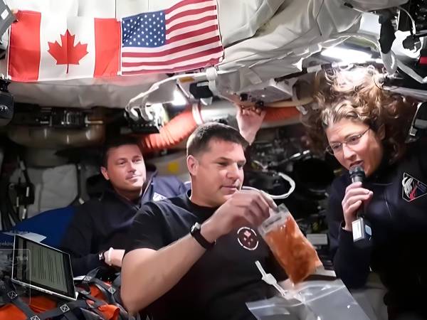 Captura de vídeo de la NASA donde aparecen los astronautas Reid Wiseman (i), Jeremy Hansen (c), y Christina Koch, mostrando los alimentos que consumen a bordo de la nave Orion de la misión lunar Artemis II.