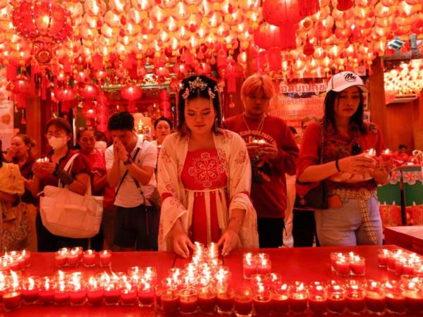 Una mujer tailandesa enfundada en un vestido tradicional chino reza y enciende velas para marcar el inicio del Año Nuevo lunar en el Templo del Loto del Dragón del barrio chino de Bangkok.
