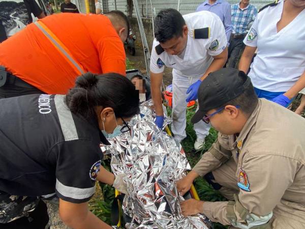 Momento en que uno de los menores desaparecidos es rescatado y atendido tras ser arrastrado por una fuerte corriente de agua en San Pedro Sula.