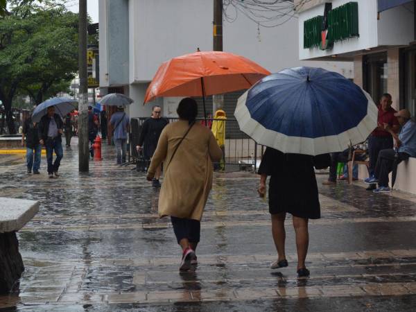 Sampedranos caminan con paraguas por el parque central de la ciudad.