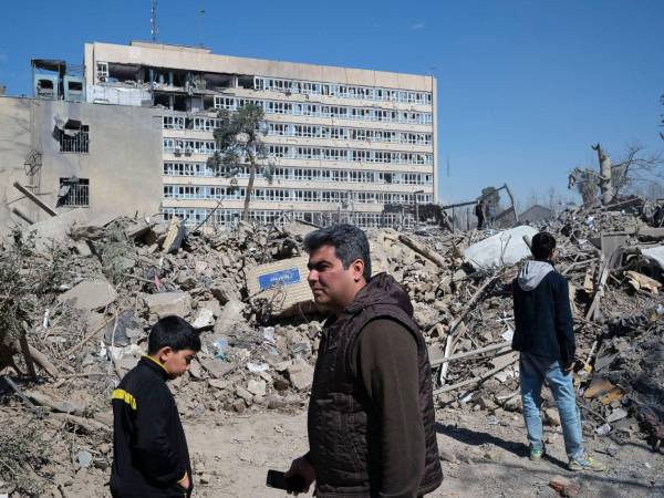 Varias personas caminan cerca de una zona alcanzada por los bombardeos israelíes-estadounidenses en los alrededores del Gran bazar de Teherán. El Ejército israelí avisó de que atacará este martes la zona industrial Hakimiya en Teherán y el Aeropuerto Internacional de Payam en Karak, en el norte de Irán.