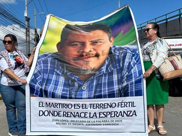 Dos mujeres sostienen un retrato del ambientalista hondureño Juan López durante una peregrinación este 13 de septiembre de 2025, en Tegucigalpa (Honduras).