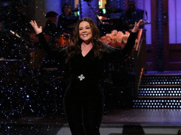 Melissa McCarthy trajo sus dotes de comedia y sirvió como inspiración en su regreso a Saturday Night Live el 6 de diciembre. La actriz y comediante mostró sus curvas con un mono de terciopelo negro cuando regresó para su sexto trabajo como presentadora de SNL.