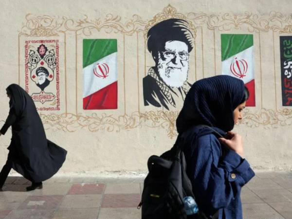 Mujeres iraníes caminan junto a un mural del difunto líder supremo iraní, el ayatolá Ali Jamenei, en una calle de Teherán, Irán.