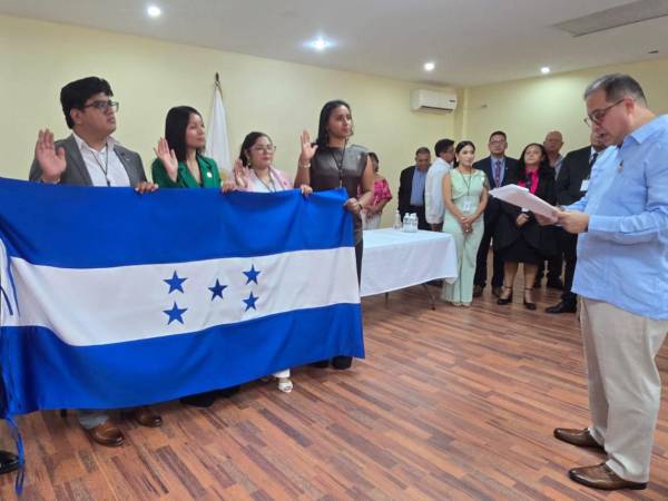 Con su mano derecha levantada y sosteniendo la bandera nacional, los nuevos miembros del Colegio de Periodistas de Honduras (CPH) prestan la promesa de ley durante la ceremonia oficial de juramentación.