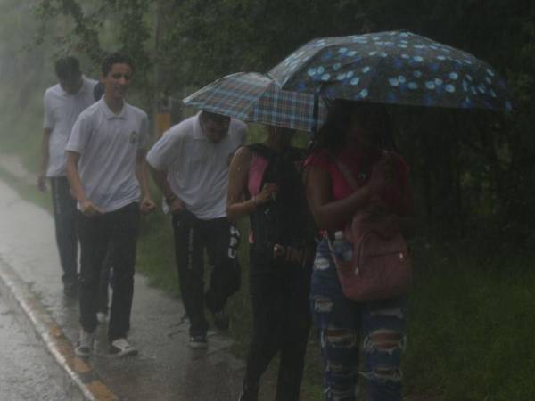 Jóvenes caminan durante una mañana lluviosa en Tegucigalpa.