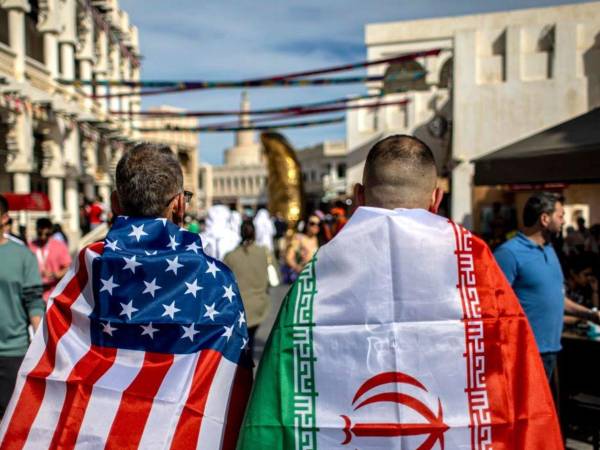 Ciudadanos de Estados Unidos e Irán, de espaldas, con sus banderas.