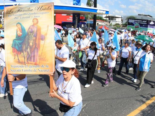 Una mujer sostiene un cartel con la imagen de la Sagrada Familia durante la marcha por la paz de ayer, sábado.