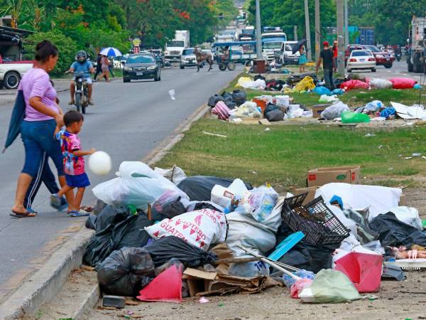 Personas transitan por la 33 calle, donde pobladores de colonias aledañas han sacado su basura a la mediana.
