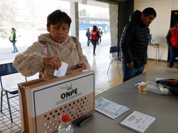 Una mujer deposita su voto en una urna este domingo, durante la segunda vuelta de las elecciones presidenciales en Perú, en Santiago.