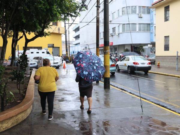 Dos mujeres caminan en la vía pública durante una tarde lluviosa en Tegucigalpa.
