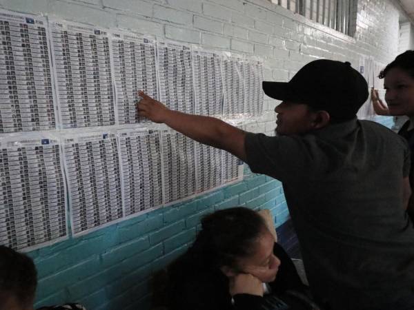 Hondureños se buscan en el padrón electoral de un centro de votación hondureño este domingo 9 de marzo.