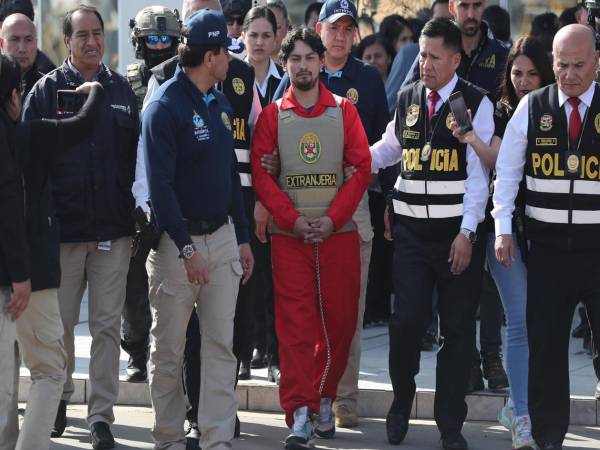 Matías Agustín Ozorio (c), de nacionalidad argentina, es trasladado por integrantes de la Policía Nacional de Perú (PNP) y de Interpol para ser entregado a la Policía Argentina este jueves, en la Base Aérea de Policía Aérea de Perú en Lima. EFE/