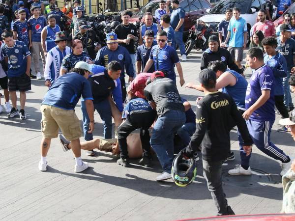 Aficionados de Motagua cargando a otro hincha que resultó herido de bala en los disturbios de barras afuera del estadio Nacional.