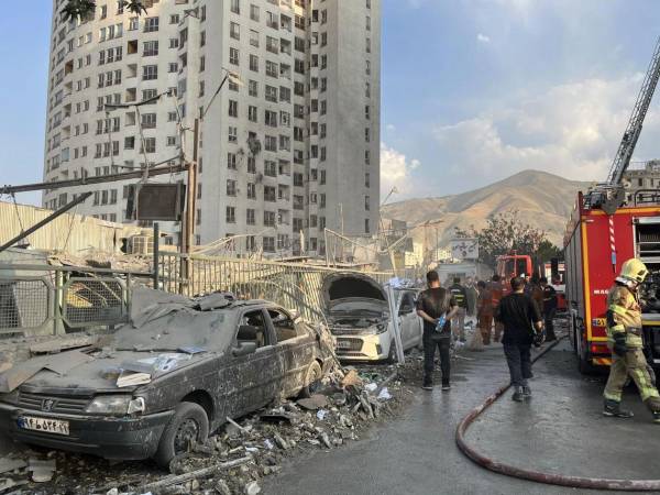 Bomberos trabajan en el exterior de un edificio alcanzado por ataques aéreos israelíes al norte de Teherán, Irán.