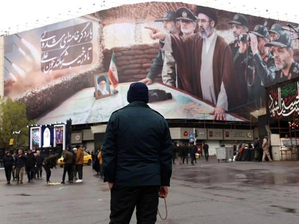 Un agente de seguridad iraní frente a una valla publicitaria.