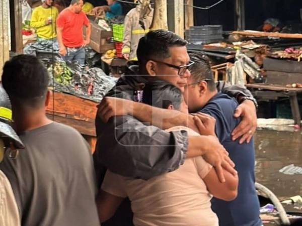 Elmer García y su esposa reciben consuelo tras perder su negocio en el pavoroso incendio.