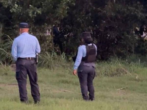 Dos agentes policiales resguardan la escena del crimen en cañera de Potrerillos.