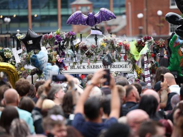 Los fanáticos toman fotos de los tributos a Ozzy Osbourne en el banco de Black Sabbath y el puente después de ver el cortejo fúnebre de Osbourne en Birmingham, Reino Unido.