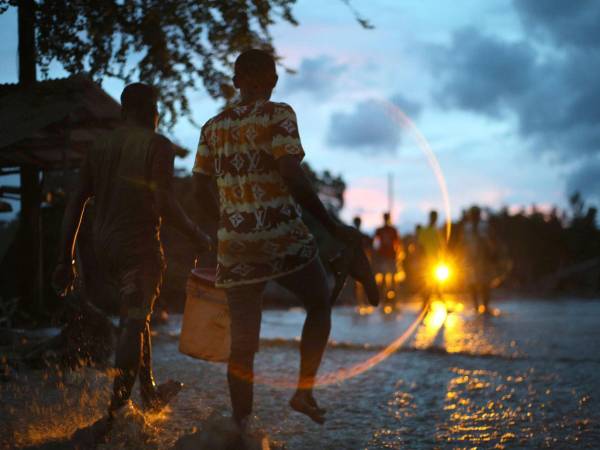 Personas caminan sobre el lodo por la creciente del río La Digue este miércoles, en Petit Goave (Haití).