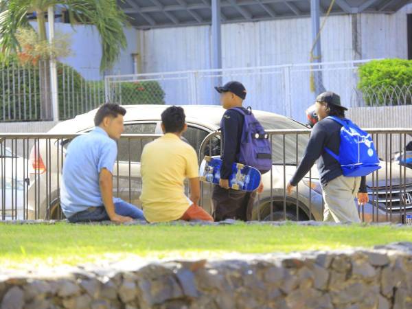 Dos hombres conversan en el parque central de San Pedro Sula, mientras dos más transitan por el lugar.