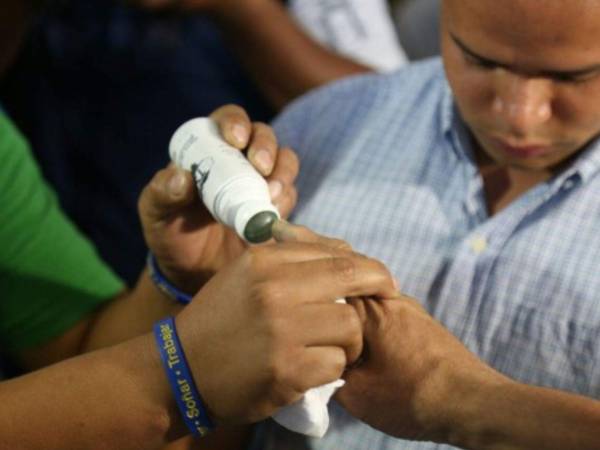 Miembro de junta receptora de votos marca el dedo de un hondureño después de ejercer el sufragio.