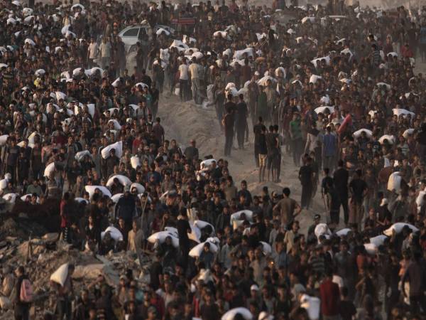 Palestinos desplazados llevan bolsas de harina por la calle Rashid, en el oeste de Jabalia, el 17 de junio de 2025, después de que camiones de ayuda humanitaria ingresaran al norte de la Franja de Gaza a través del cruce de Zikim, controlado por Israel, al noroeste de la ciudad de Gaza. EFE