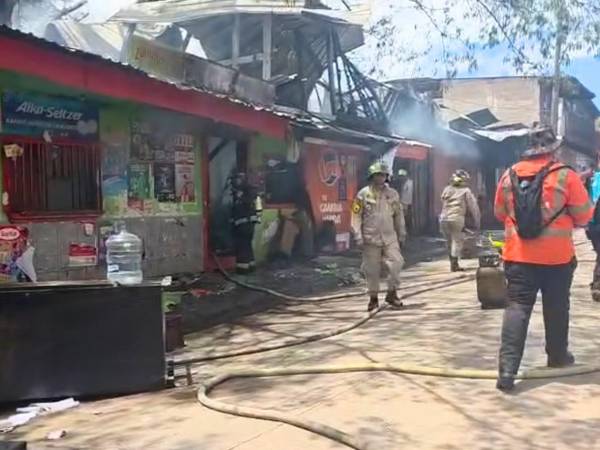 Negocio consumido por las llamas, mientras el Cuerpo de Bomberos realiza labores de emergencia para sofocar el incendio.