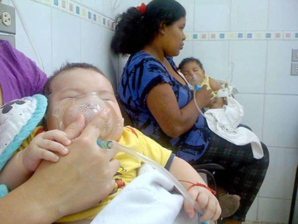 Dos mujeres sostienen las mascarillas de sus hijos en un centro asistencial de Honduras en una fotografía de archivo.