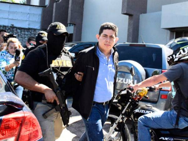 Suárez antes de ingresar a una audiencia, custodiado por agentes.