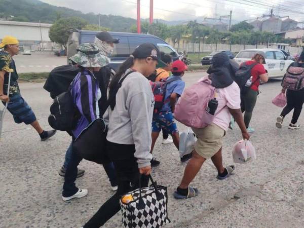 Migrantes hondureños avanzan con sus pertenencias por las calles de San Pedro Sula como parte de la nueva caravana que se dirige hacia Estados Unidos.