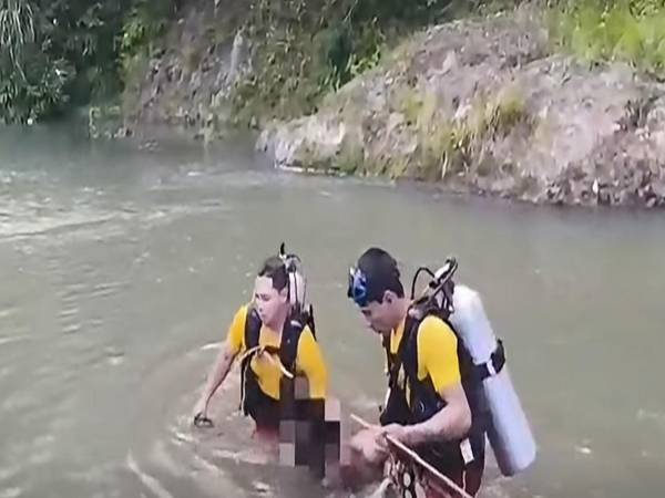 Bomberos rescatan los cadáveres y los llevan a la orilla.
