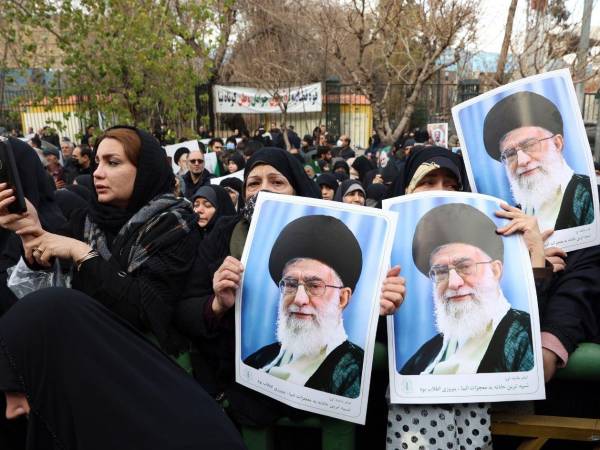 Un grupo de manifestantes prorégimen en Irán muestra unas fotos del líder supremo, el ayatolá Alí Jamenei, durante el funeral celebrado por los policías muertos durante las manifestaciones de protesta contra el régimen.