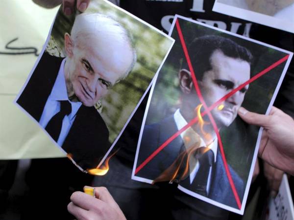 Una persona prende fuego a dos fotografías del presidente sirio, Bachar al Asad (derecha), y de su padre, Hafez, durante una manifestación en Estambul (Turquía).