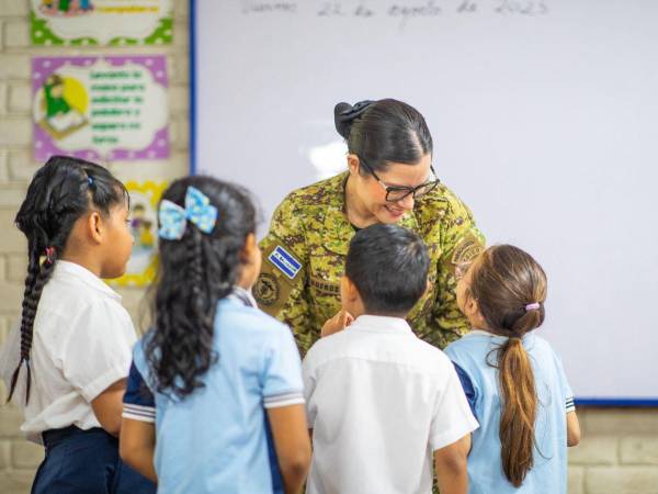 La ministra de Educación, Karla Trigueros, saluda a niños de una escuela salvadoreña.