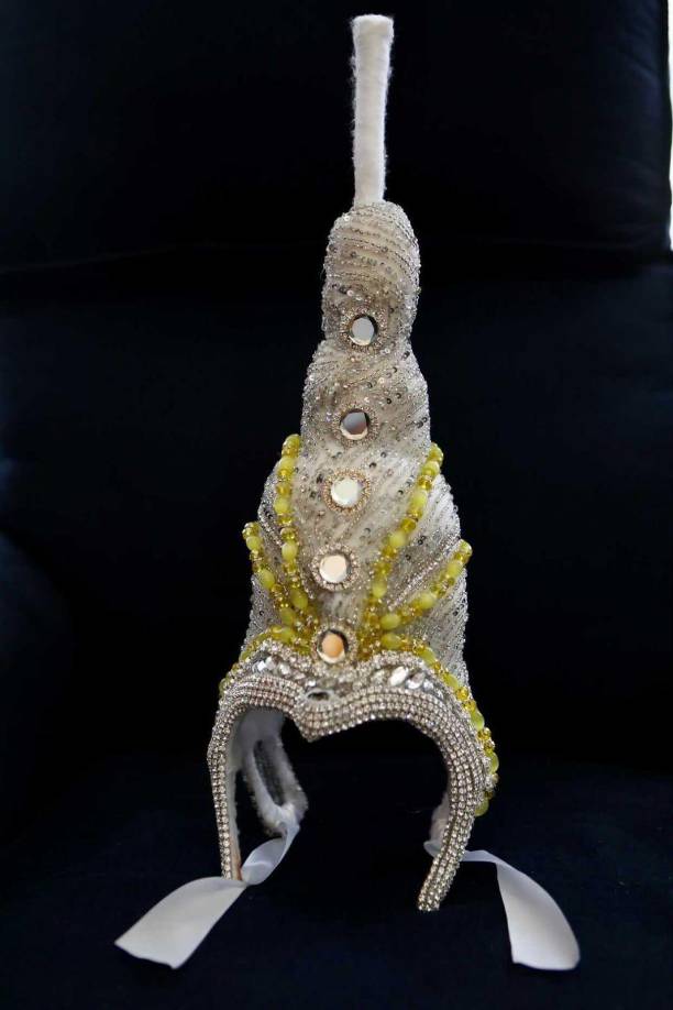 En la base de la corona lleva un bordado totalmente a mano de pedrería en mini canutillos y cuencas de Crystales Swarovski , y unas piedras grandes simulando el espejo que en el traje original lleva. La corona cuenta con unos mosaicos de colores que tienen un significado especial: el verde significa esperanza mientras que el amarillo, sabiduría, inteligencia y amor. 