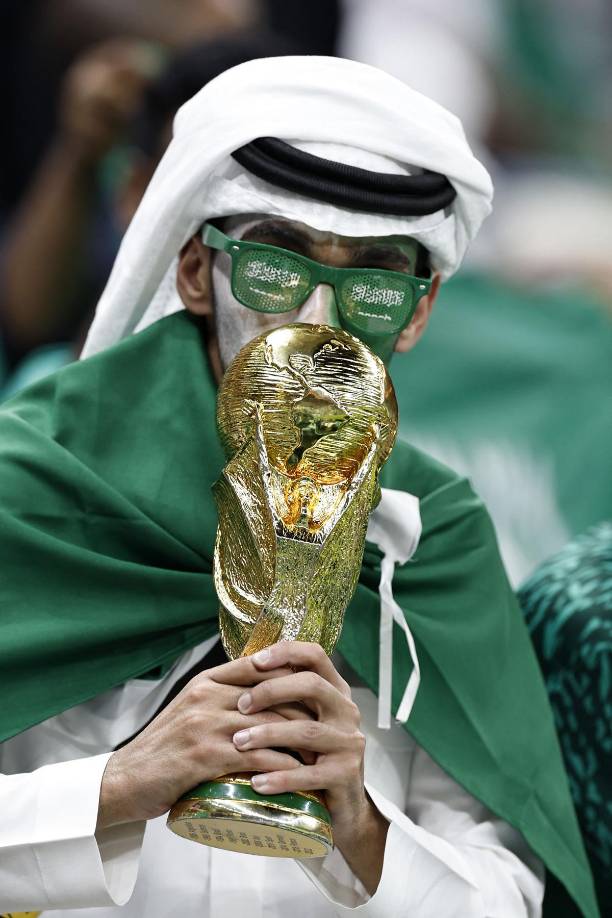 Aficionados saudíes con una copia pequeña de la Copa del Mundo.
