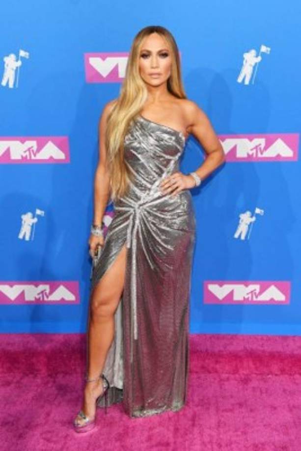 Primero, López adornó la alfombra púrpura con un vestido plateado con detalles de cristal Swarovski y una abertura alta en la pierna.<br/>Para completar usó sandalias de plataforma y accesorios del mismo tono.