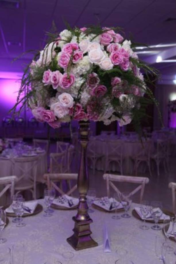 Candelabros con bolas de rosas y hortensias con destellos silvestres. Los tonos marfil y rosa medieval pintaron de elegancia en combinación con iluminación led púrpura y cortinajes de shifón. <br/>