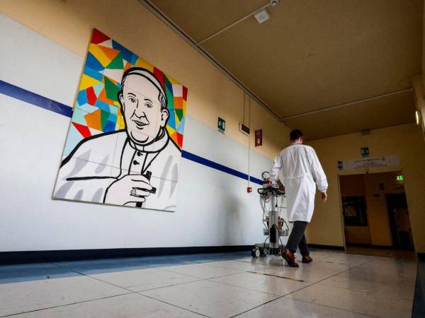 Un médico pasa junto a un mural que representa al Papa Francisco dentro del Hospital Gemelli, donde está hospitalizado, en Roma, Italia.