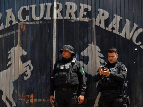 Agentes de la policía resguardan el rancho donde supuestamente se encontraron restos humanos.