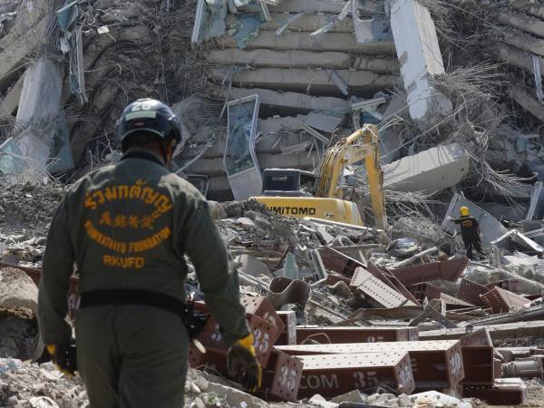 Socorrista observa los escombros de un edificio derrumbado.