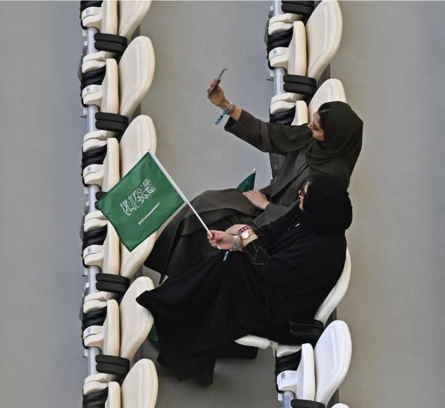 Aficionadas saudíes vestidas con una abaya negra y apoyando a su selección con banderas.
