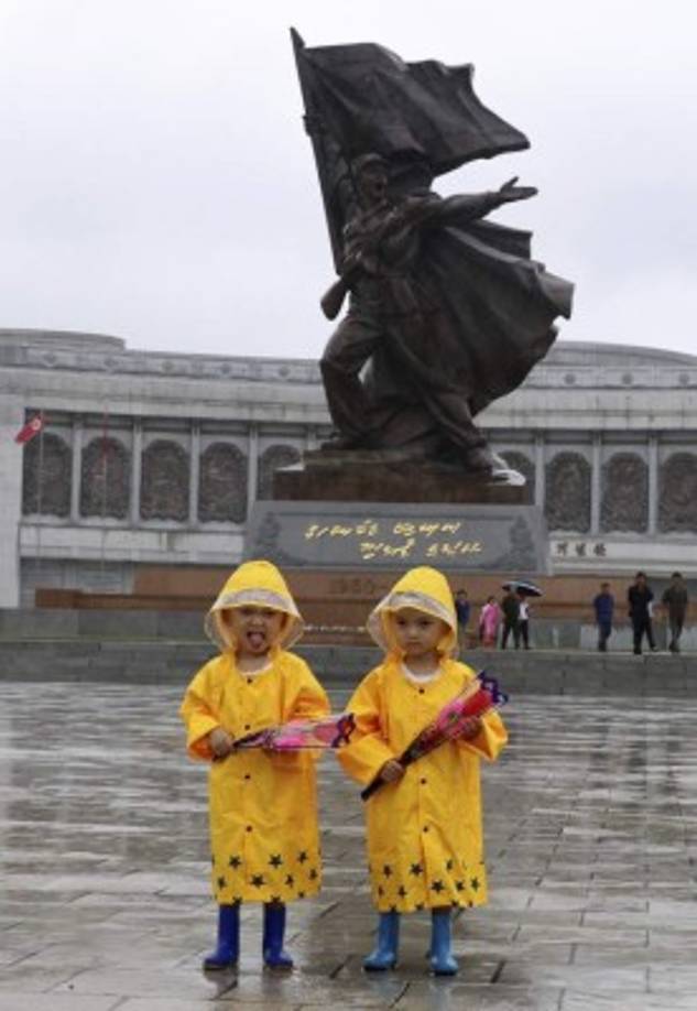 Dos gemelos posan con chubasqueros en un día lluvioso ante el Monumento a la Victoria en la Guerra de Liberación de la Patria en Pyongyang.