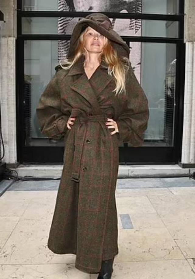 Pamela ha estado mostrando con orgullo su cutis desnudo en una gran cantidad de desfiles de la Semana de la Moda, y el de Westwood no fue diferente. La veterana de Baywatch posó con una gabardina de gran tamaño de color verde oliva con un estampado de rayas rojas y un sombrero a juego.
