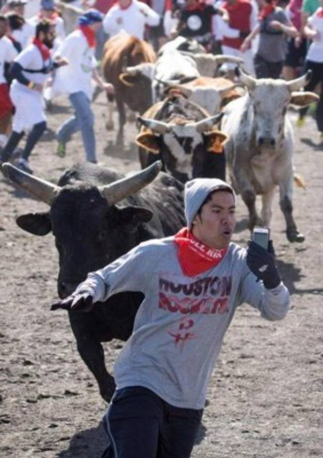 Este joven es temerario: intenta fotografiarse o grabarse mientras corre por salvar su vida cuando es perseguido por varios toros.